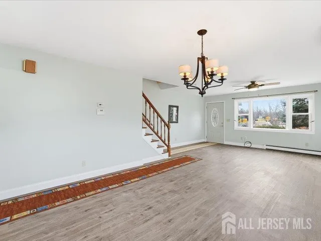 a view of a room with wooden floor chandelier and windows
