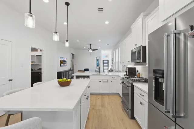 a kitchen with a refrigerator a stove and white cabinets with wooden floor