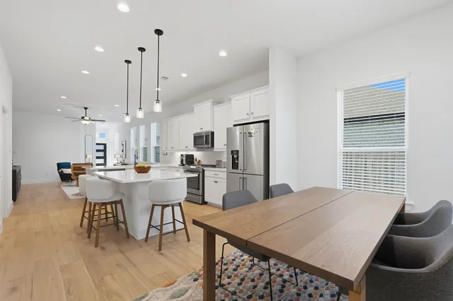 a dining room with stainless steel appliances kitchen island granite countertop a dining table chairs and a refrigerator