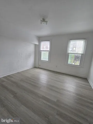 a view of an empty room with wooden floor and closet
