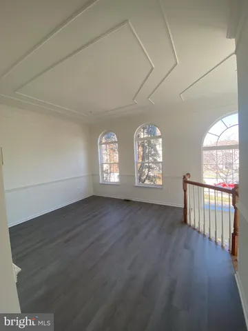 an empty room with wooden floor windows and entrance