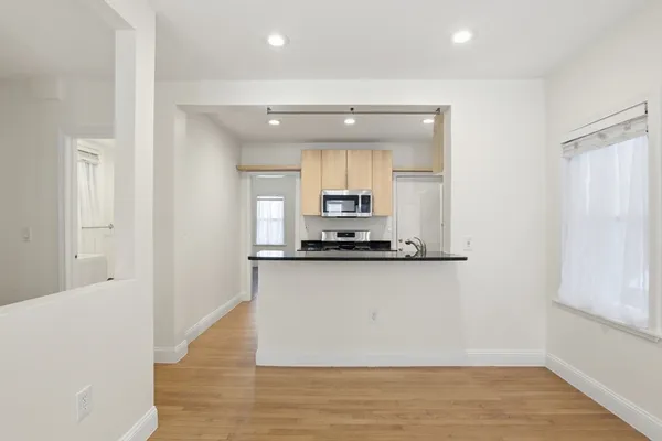 a large white kitchen with kitchen island a sink wooden floor and a refrigerator