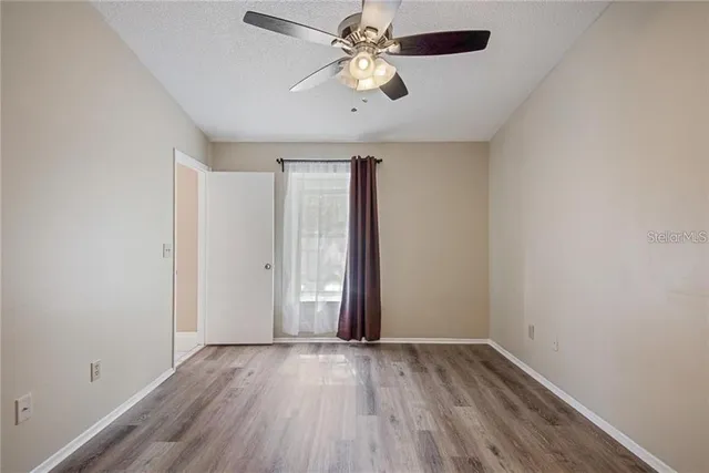 an empty room with wooden floor chandelier fan and closet area
