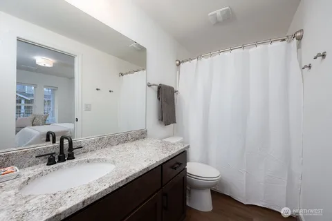 a bathroom with a granite countertop sink toilet and shower