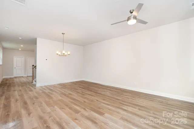 a view of empty room with wooden floor and ceiling fan