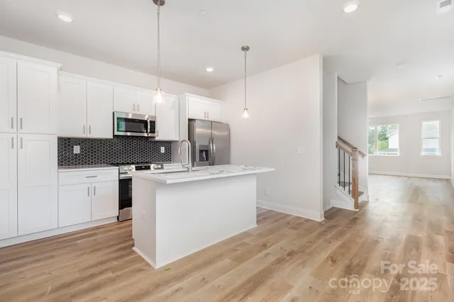 a kitchen with kitchen island granite countertop a sink appliances and wooden floor