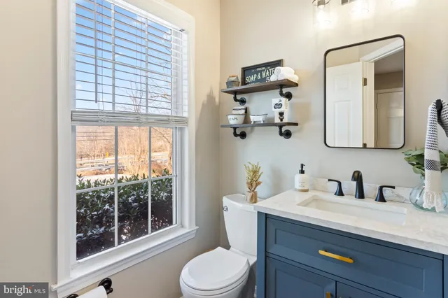 a bathroom with a toilet a sink a mirror a window and vanity