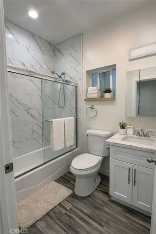 a bathroom with a granite countertop toilet a sink and a mirror