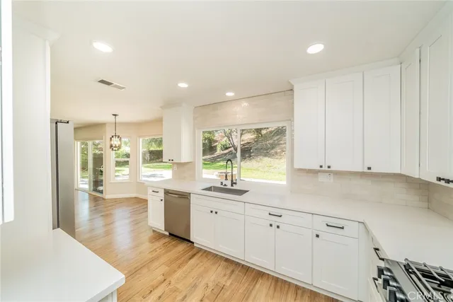 a large kitchen with stainless steel appliances granite countertop a stove a sink and a granite counter tops with a large window