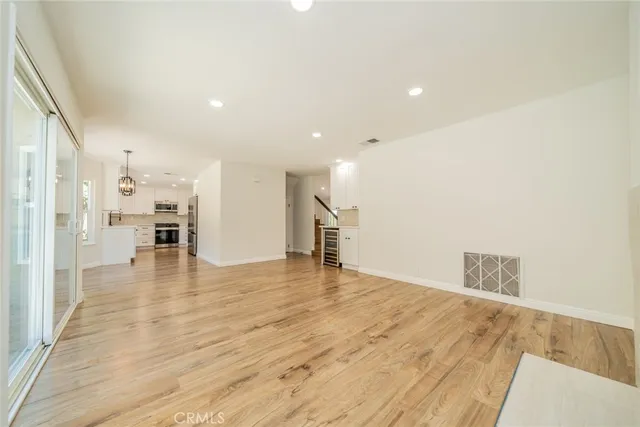 an empty room with wooden floor ceiling fan and windows
