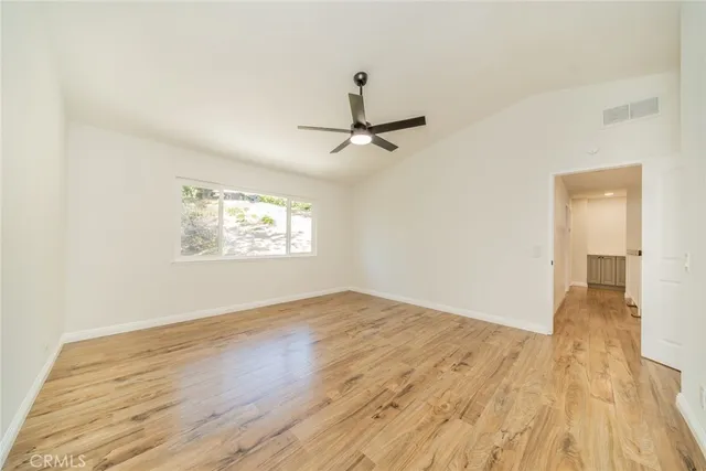 an empty room with wooden floor and ceiling fan