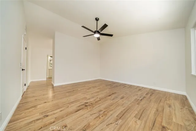 an empty room with wooden floor ceiling fan and windows