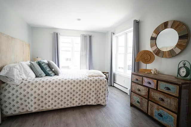 a bedroom with a bed and dresser with wooden floor