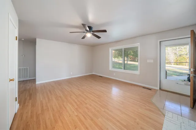 a view of empty room with wooden floor and fan