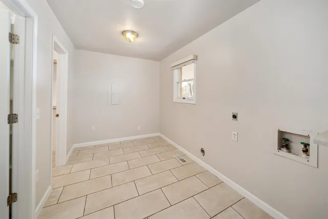 a view of an empty room with window and chandelier fan