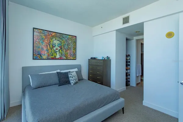 a bedroom with a bed and painting on the wall