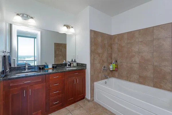 a bathroom with a tub a sink double vanity and a mirror
