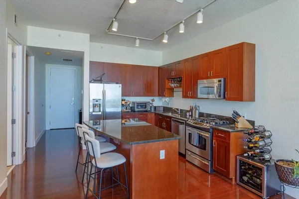 a kitchen with stainless steel appliances granite countertop a stove a sink dishwasher and a refrigerator with wooden floor