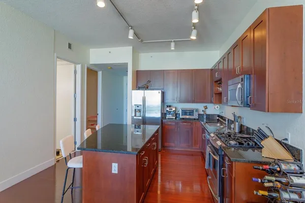 a kitchen with stainless steel appliances granite countertop a refrigerator a stove and a sink