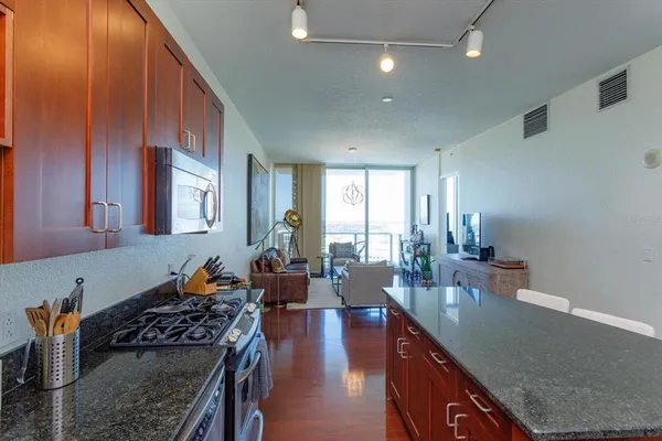 a kitchen with stainless steel appliances granite countertop a stove a sink dishwasher and cabinets with wooden floor