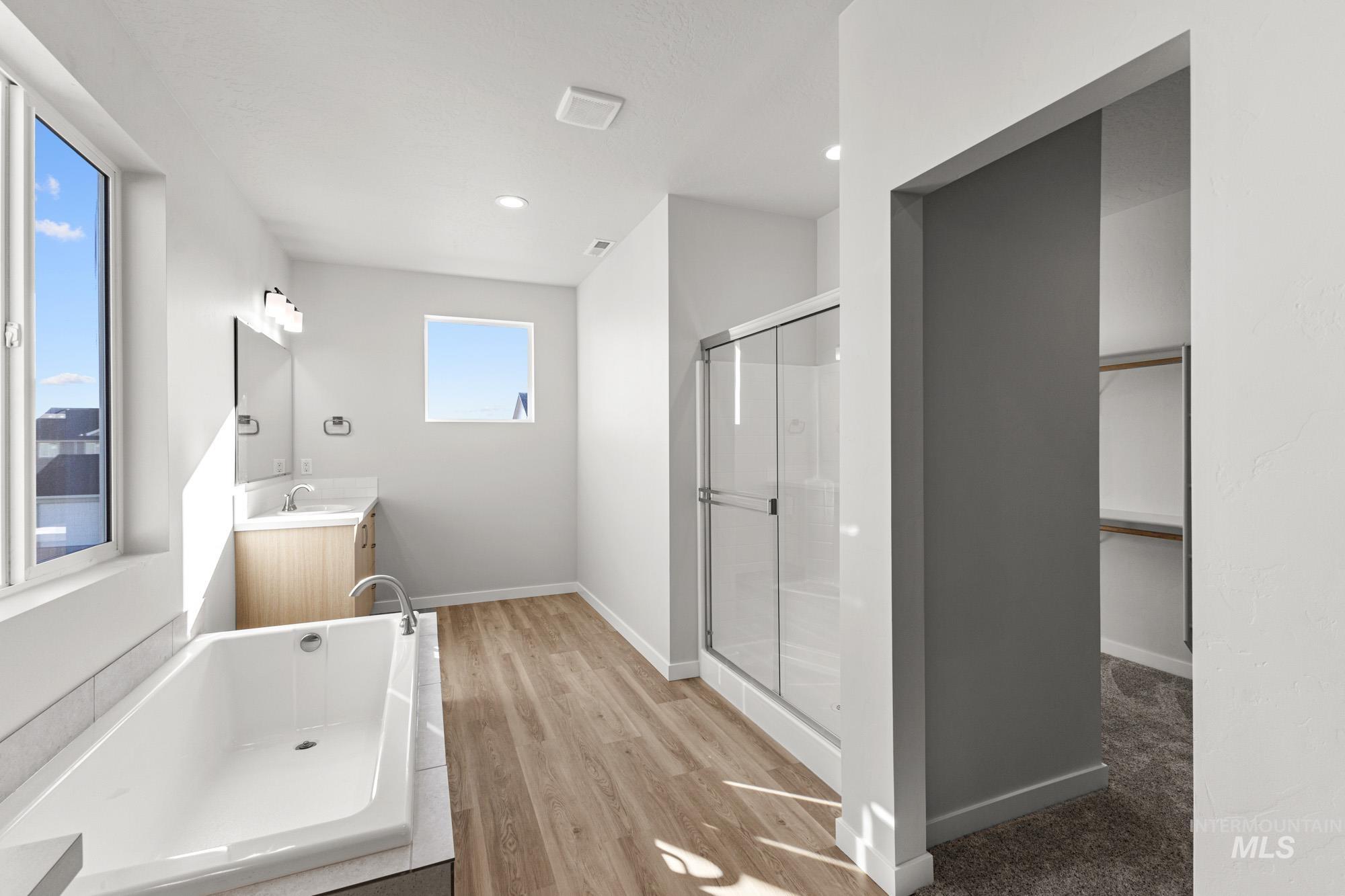 13708 Judson Street Caldwell, ID 83607 - Photo 27 of 29 Bathroom with a shower stall, vanity, a garden tub, light wood-style flooring, and a walk in closet