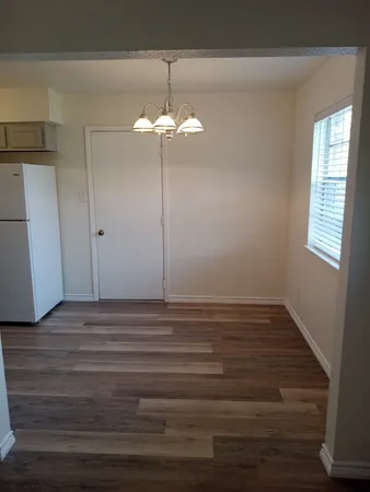 an empty room with wooden floor chandelier fan and windows