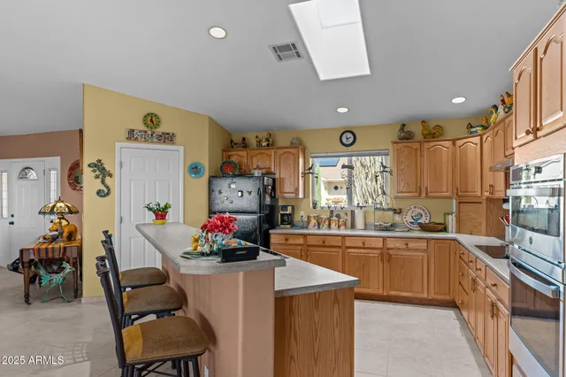a kitchen with stainless steel appliances granite countertop a dining table chairs and a refrigerator