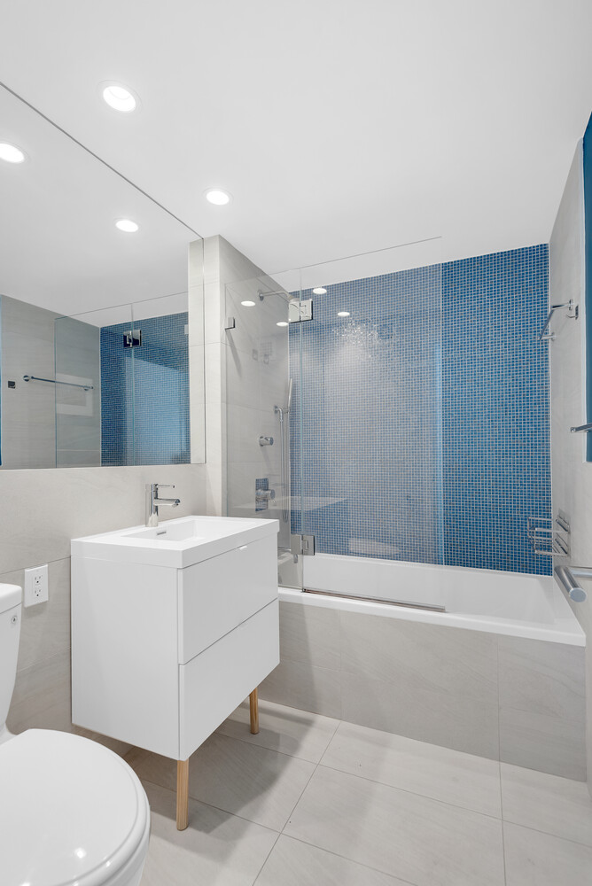 45 Sutton Place South, Unit 11J Manhattan, NY 10022 - Photo 7 of 19 a bathroom with a bathtub a toilet a sink and mirror