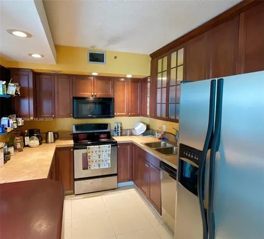 a kitchen with stainless steel appliances a stove refrigerator a sink and dishwasher with wooden floor