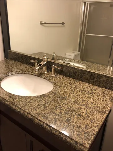 a bathroom with a granite countertop sink and a mirror