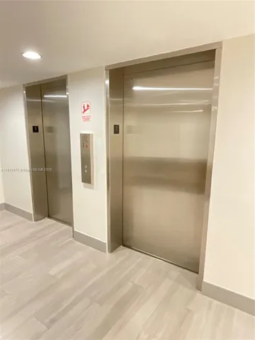 a view of an empty room with wooden floor and a bathroom