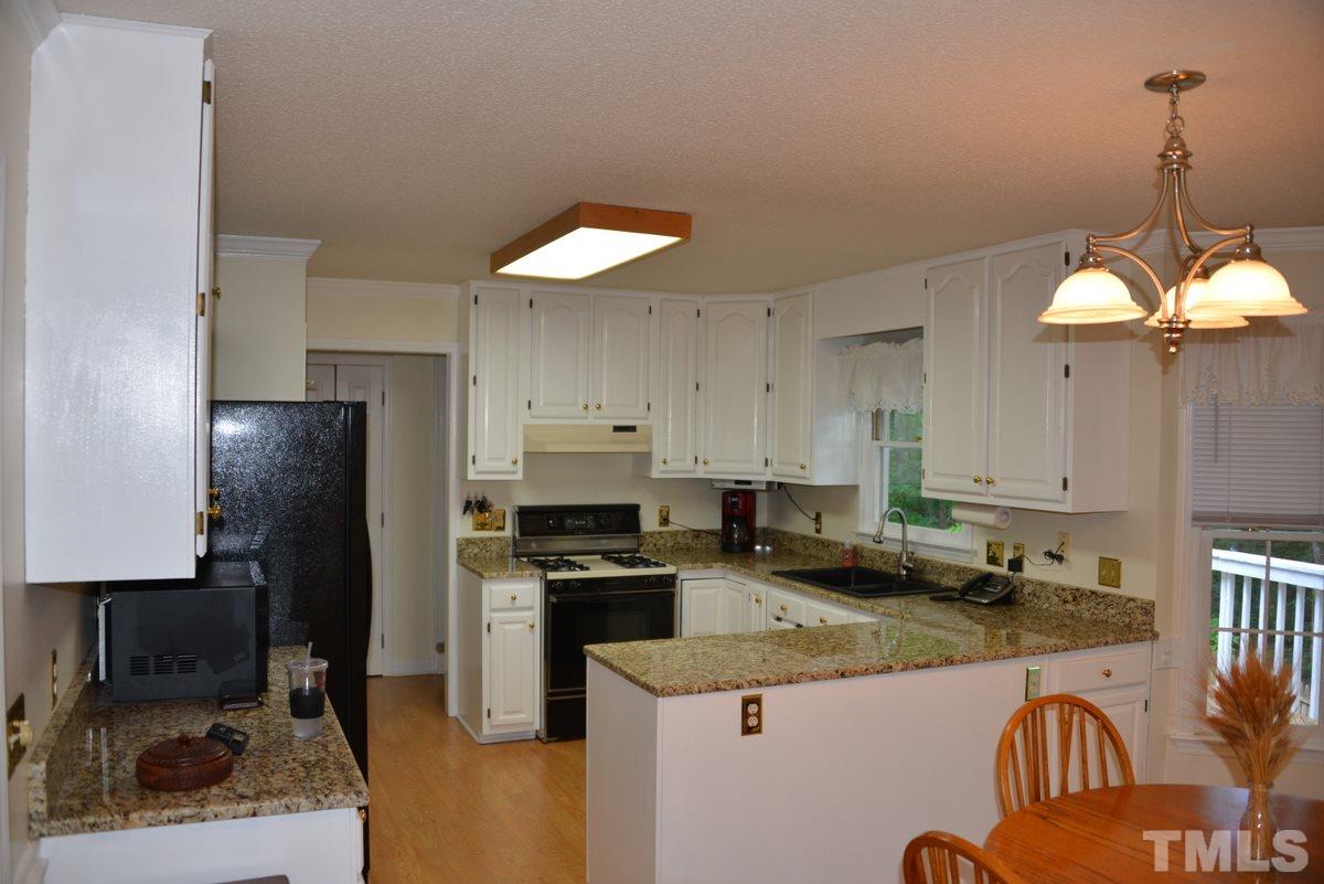 1500 Pecore Place Raleigh, NC 27615 - Photo 7 of 25 a kitchen with granite countertop a sink a counter top space stainless steel appliances and cabinets