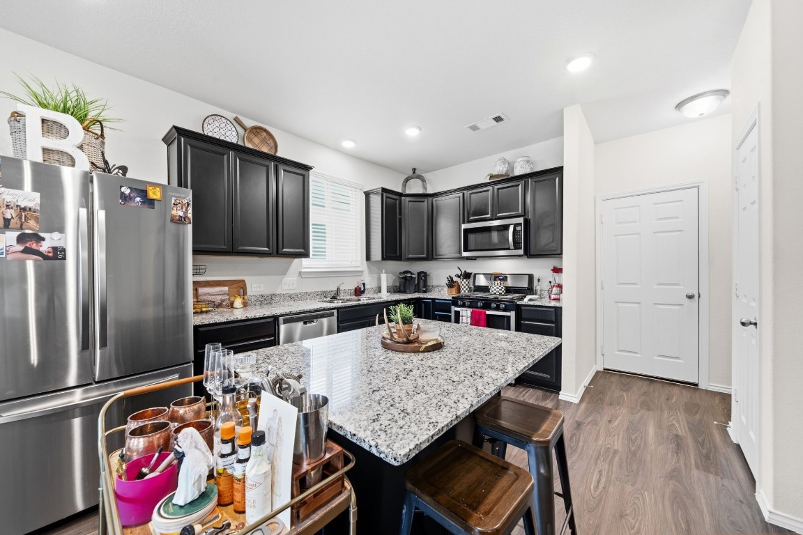 4041 Timber Sapp Drive Conroe, TX 77304 - Photo 5 of 14 a kitchen with granite countertop kitchen island stainless steel appliances a sink refrigerator stove and microwave