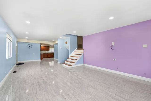 a view of an empty room with wooden floor and stairs