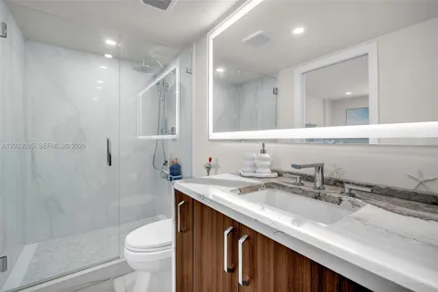 a bathroom with a granite countertop sink a toilet a mirror and shower