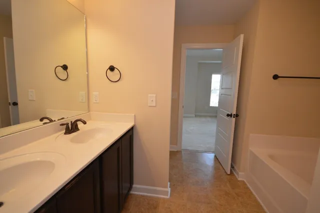 a bathroom with a double vanity sink a mirror and a bathtub