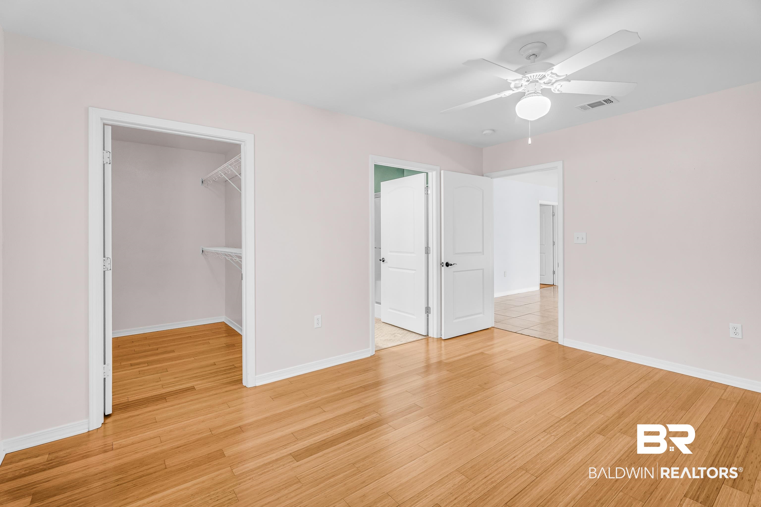 22095 8th Street Silverhill, AL 36576 - Photo 30 of 42 Unfurnished bedroom featuring ceiling fan, a walk in closet, and light wood-style flooring