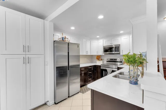 a kitchen with stainless steel appliances kitchen island granite countertop a refrigerator a sink a stove a dining table and chairs