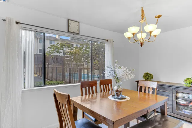 a view of a dining room with furniture a chandelier and large windows