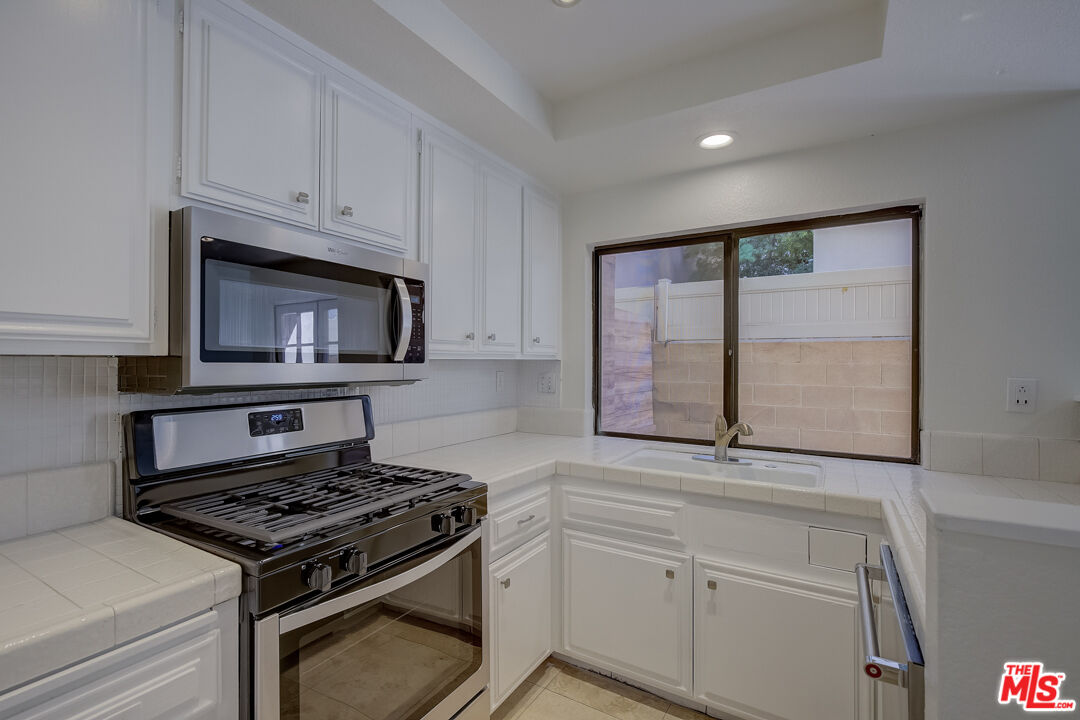 117 East Wilson Street, Unit C Costa Mesa, CA 92627 - Photo 2 of 23 a kitchen with white cabinets and appliances