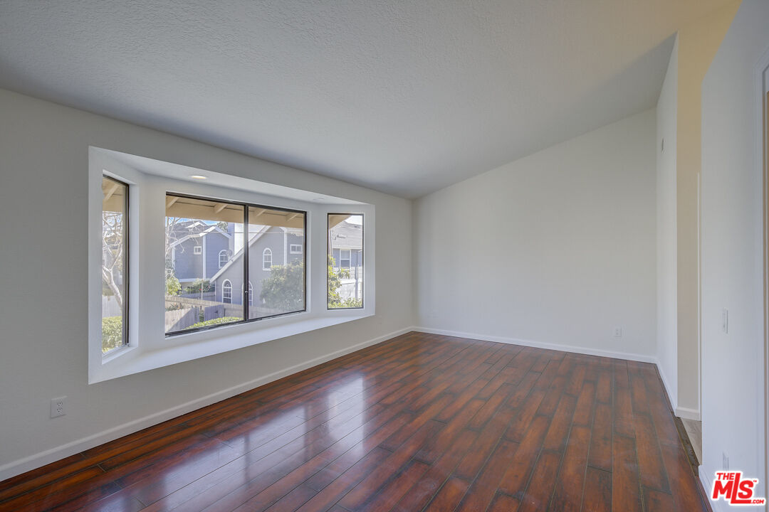 117 East Wilson Street, Unit C Costa Mesa, CA 92627 - Photo 7 of 23 a view of an empty room with a window and wooden floor