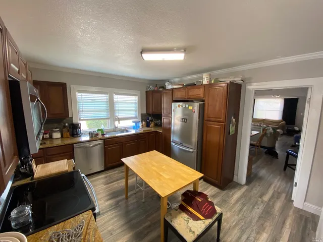 a kitchen with refrigerator a sink dishwasher and wooden cabinets with wooden floor