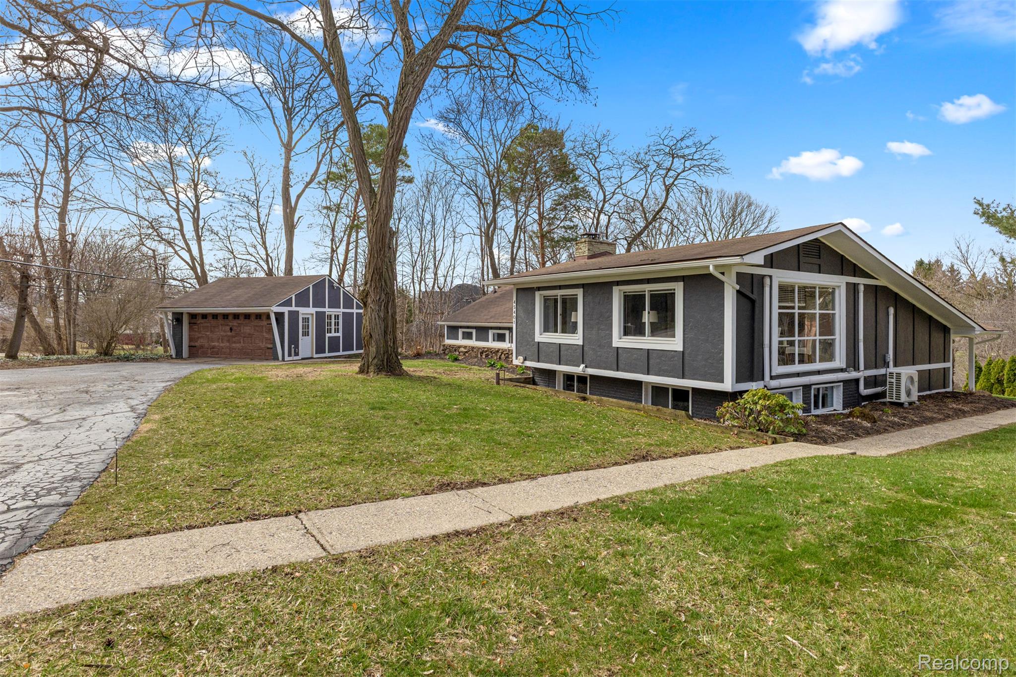 45401 West 9 Mile Road Novi, MI 48374 - Photo 51 of 67 View of property exterior featuring an outdoor structure, a sunroom, a garage, a chimney, and a lawn