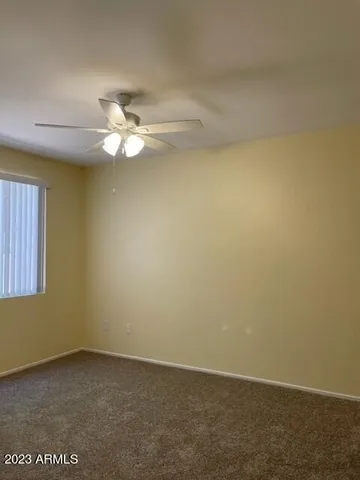 an empty room with a window and a ceiling fan