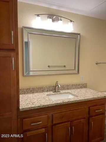 a bathroom with a granite countertop sink a mirror and cabinets