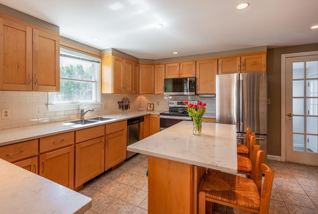4 Graystone Road Gloucester, MA 01930 - Photo 16 of 34 a kitchen with stainless steel appliances granite countertop a refrigerator a sink dishwasher a stove a dining table and chairs with wooden floor