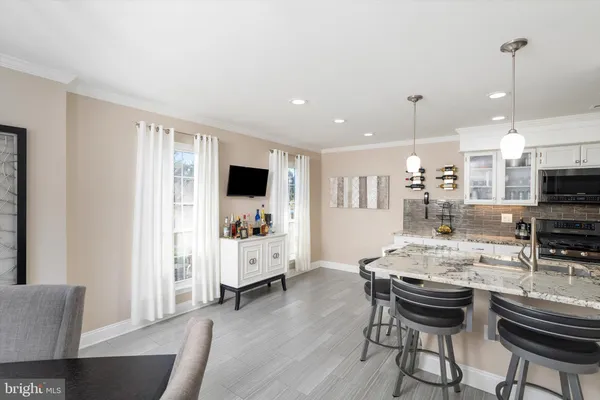 a kitchen with stainless steel appliances kitchen island granite countertop a stove a sink a dining table and chairs with wooden floor