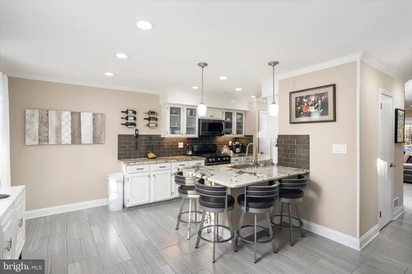 a kitchen with a dining table chairs cabinets and wooden floor