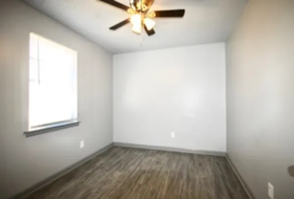 an empty room with a window and a fan