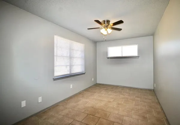 an empty room with windows and fan